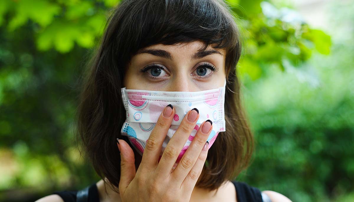 a young woman wears a respirator mask outside
