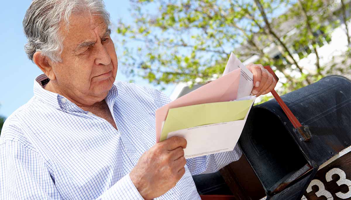  worried older man checks mailbox