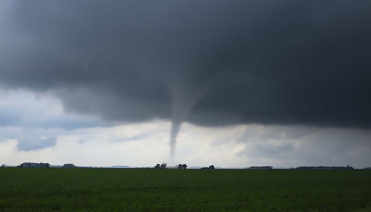 A tornado rampages over a green field