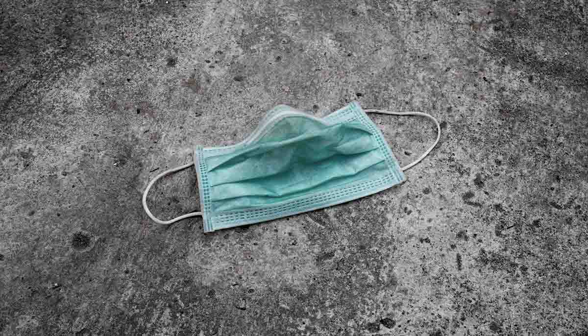 a disposed face mask laying on pavement