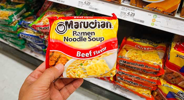  a hand holds up a package of Maruchan Ramen Noodles
