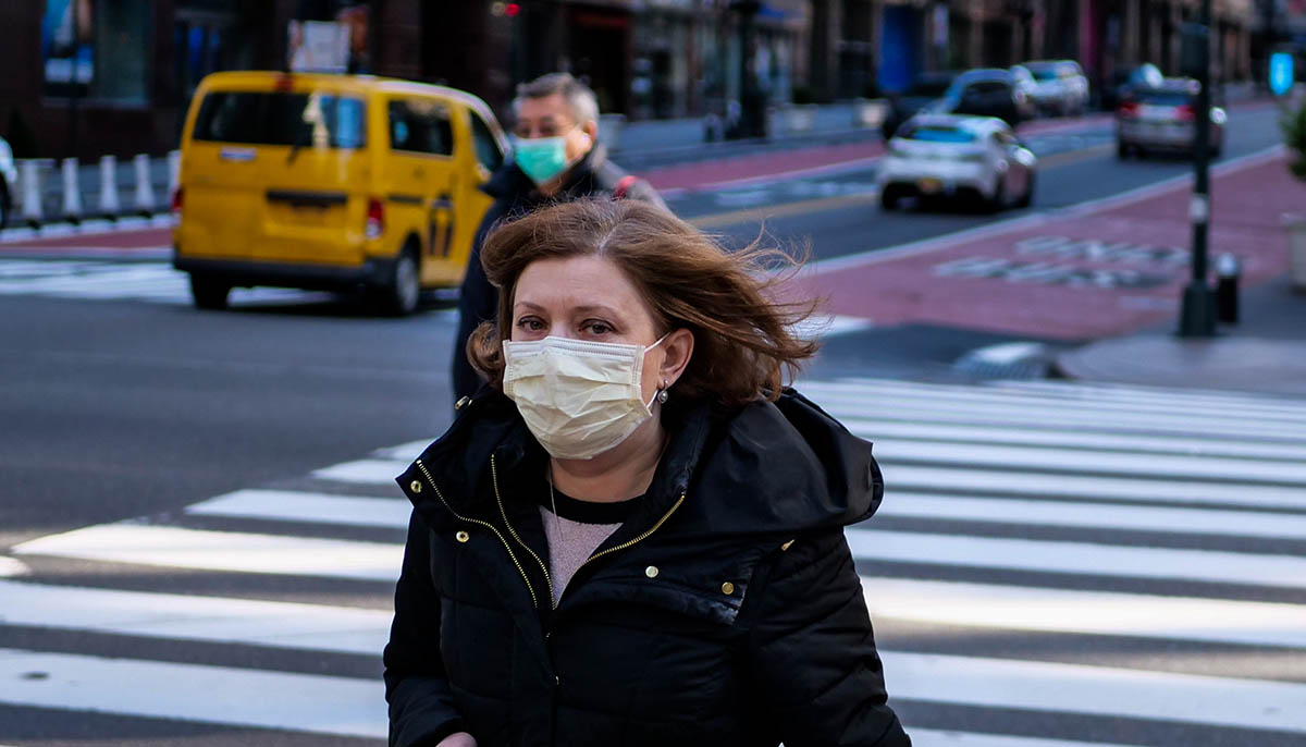 a woman with a mask walks through empty New York streets