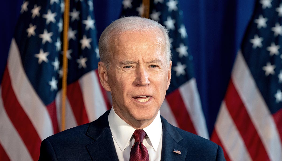 Joe Biden speaks in front of multiple american flags