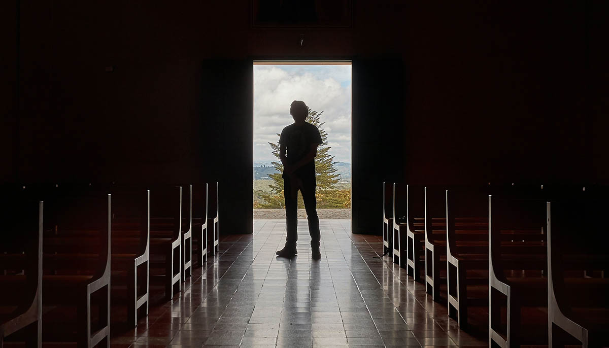 silhouette of a man inside of a dark church entrance