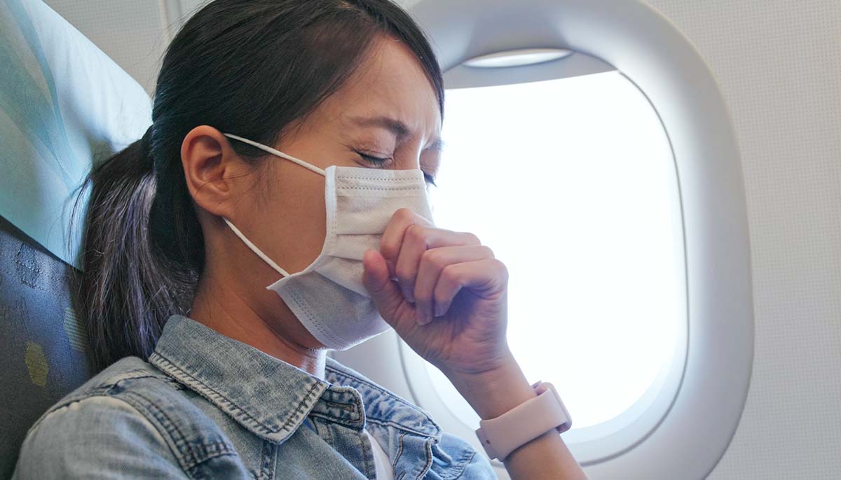  a woman feels unwell while wearing a face mask on an airplane