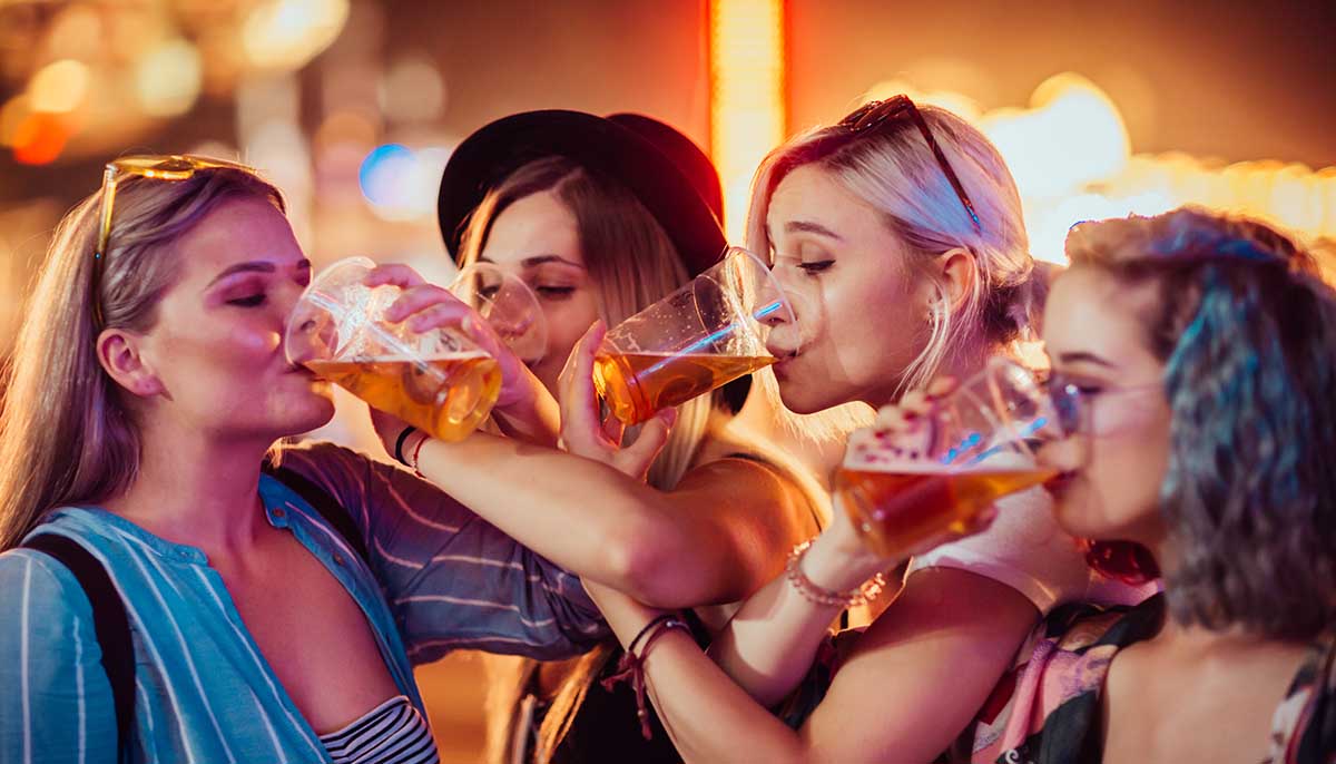 a group of female friends drink together at a bar