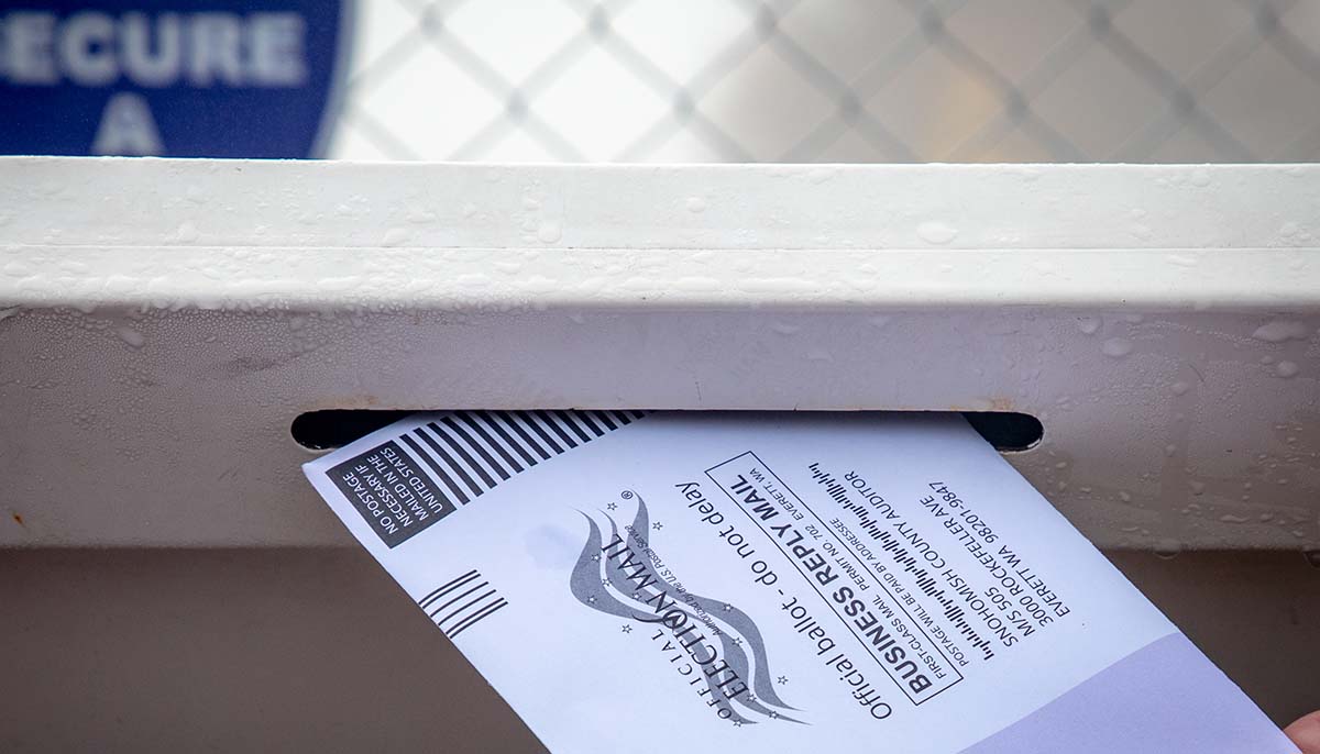 a person places a mail in ballot into a slot