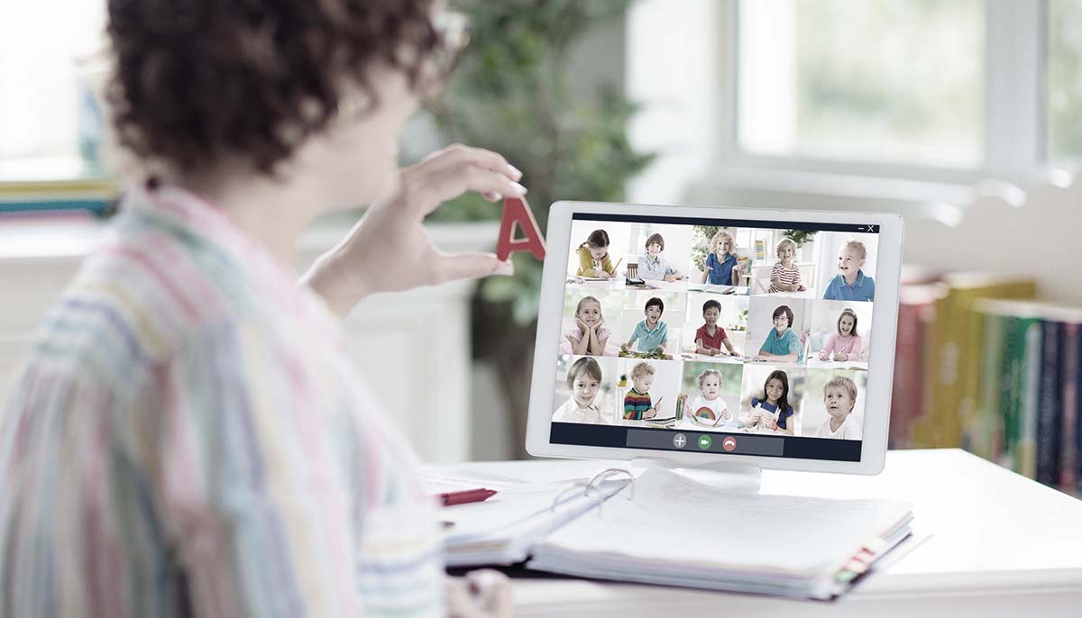 a teacher teaches children over a computer in a zoom class