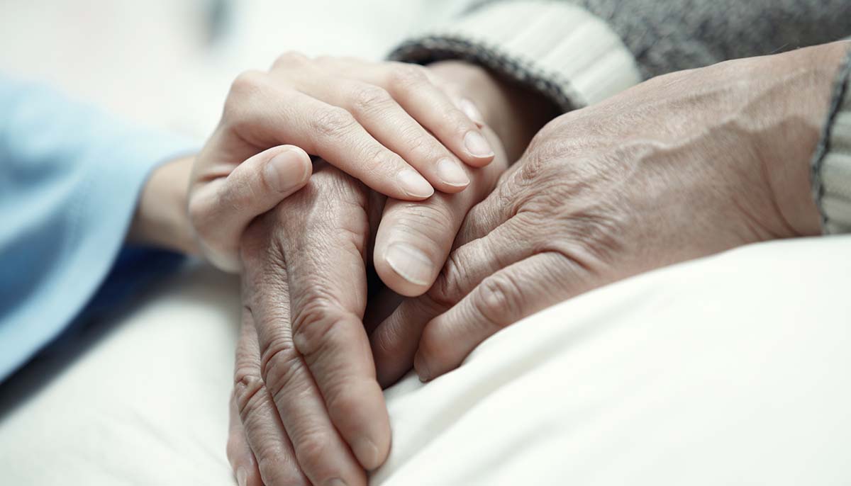  elderly couple holds hands in hospital