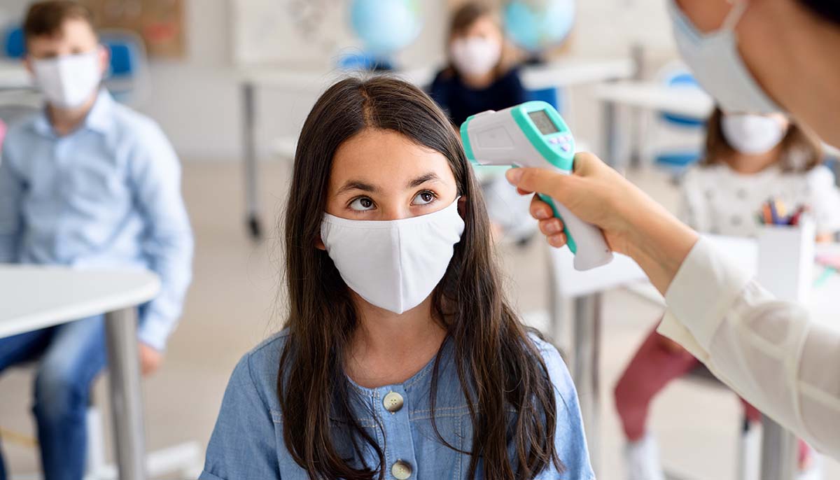 student gets temperature checked at school while wearing a mask