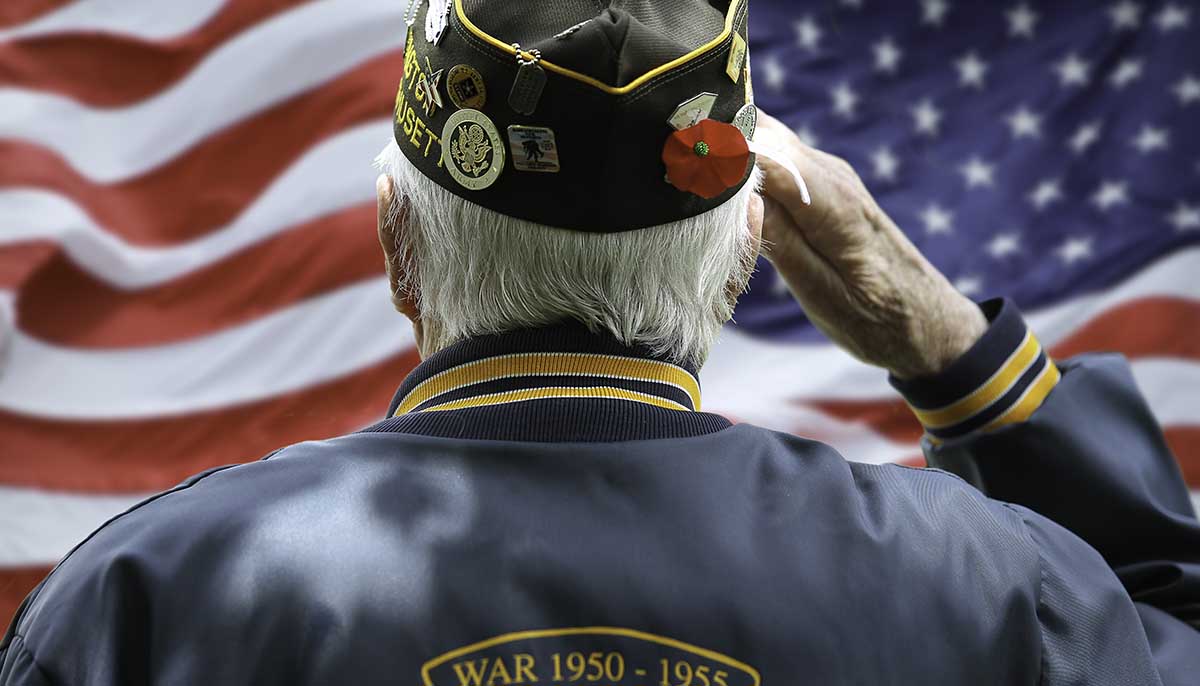 veteran salutes in front of an American flag